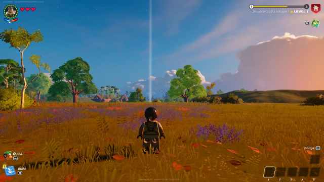 Personaje LEGO en hierba marrón mirando la columna de luz del punto de referencia establecida en la distancia.