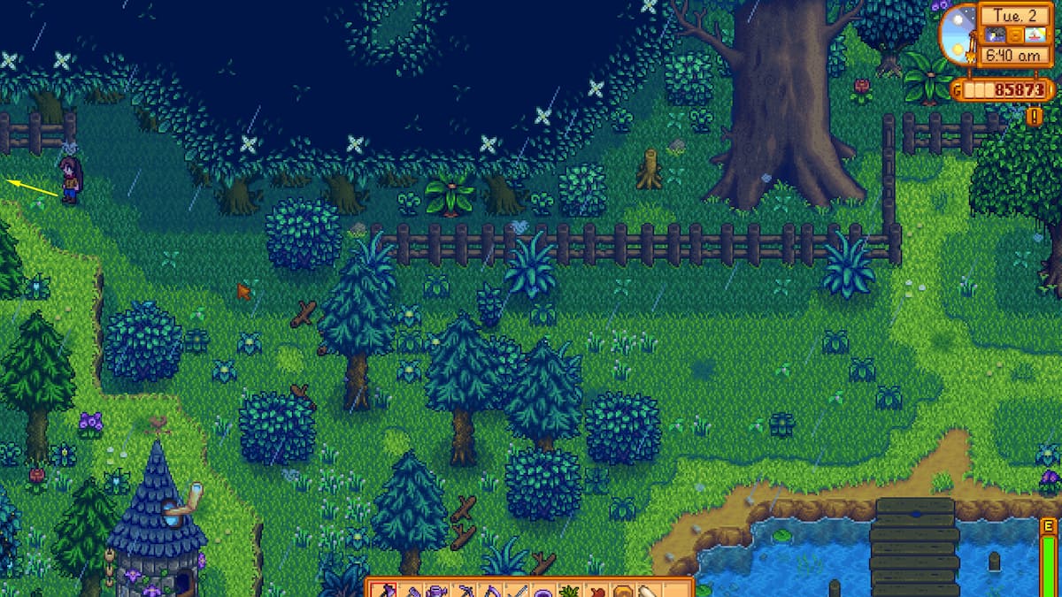 Flecha amarilla que apunta a la entrada del bosque secreto, justo encima del mago, en el área sur de la granja.